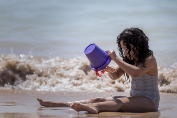 Niña jugando en la playa con la arena.