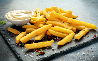 Homemade Baked Potato Fries with Mayonnaise, salt, pepper on black stone board
