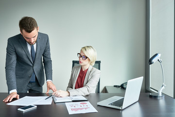 Portrait of two successful business people working at desk in modern office  reading financial documents and analyzing marketing statistics