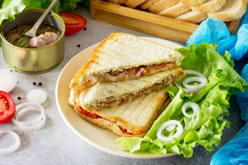 Double sandwich with canned tuna and feta cheese served with lettuce leaves on a background of gray stone.