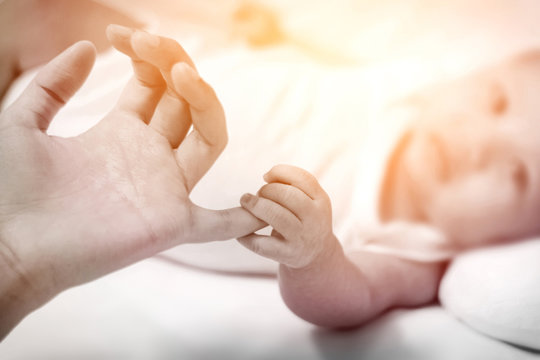 Soft tone of image of Close up a newborn baby's hand clutching his mother fingers.