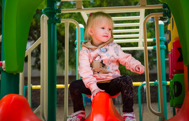 Little girl of three-years comes down from the slide on the playground.