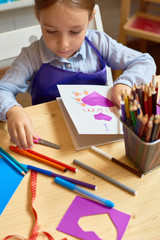 Portrait of adorable little girl  making gift card for mom during art and craft class in pre-school