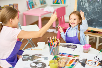 Portrait of two little girls enjoying art and craft lesson in development school and having fun