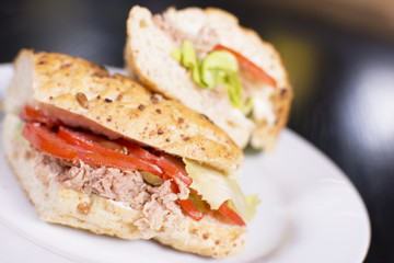 Fresh sandwich with ham, cheese, bacon, tomatoes, lettuce, cucumbers and onions on dark wooden background. Delicious restaurant meal.