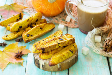 Freshly baked raisins and cinnamon biscotti and a cup of cappuccino coffee on a kitchen wooden table.