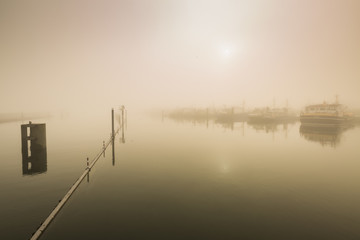 Fototapeta premium Fishing boats awaiting delayed departure in harbour due to heavy fog