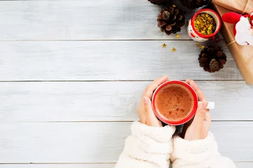 Crédence de cuisine en verre imprimé Chocolat main féminine tenant une tasse de chocolat chaud ou de chocolat avec un cadeau de Noël sur une table en bois d& 39 en haut