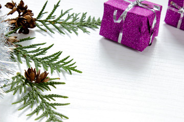 Small Christmas tree decorated with toys stands on the table with red cones on a bright purple background for an inscription.
