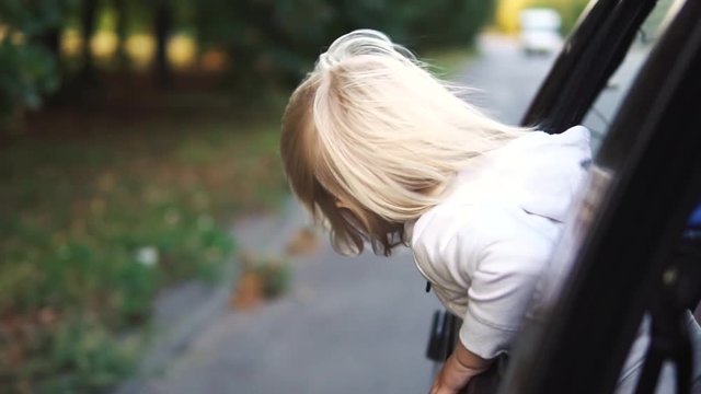 Kid with hair in the wind riding in the car.