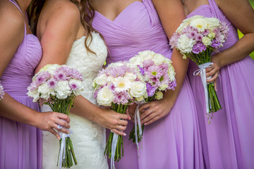 A bride and bridesmaids in purple dresses holding their bouquets and flower