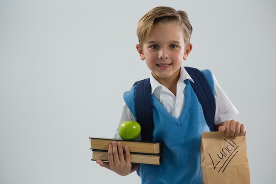 Smiling Schoolboy Holding Books And Lunch Paper Bag