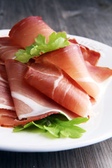 Italian prosciutto crudo or jamon. Raw ham on white dish.