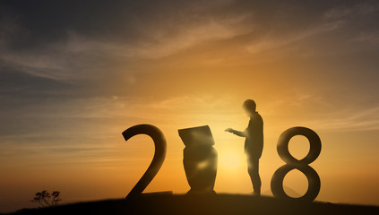 futuristic concept, Silhouette friendship man put a hand on to command the robot (artificial intelligence) on the top of the mountain with sunset background and celebrating 2018 new years