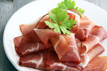 Italian prosciutto crudo or jamon. Raw ham on white dish.
