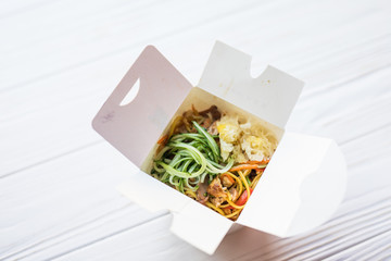 Noodles in a white box on a wooden background close up shot