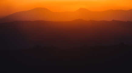 Fototapeta na wymiar A beautiful colorful sunset in mountain ridge with glowing red haze