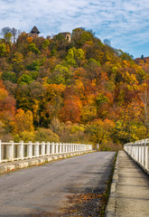 Fototapeta na wymiar Nevytsky Castle, Ukraine - October 27, 2016: bridge to Nevytsky Castle hill with yellow foliage in autumn forest. popular tourist attraction