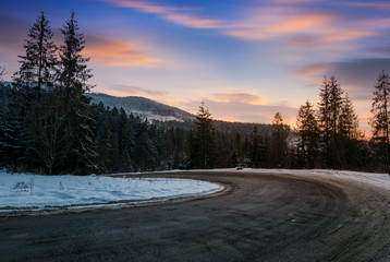serpentine in winter mountains at sunset. gorgeous landscape with dark spruce forest on hillsides...