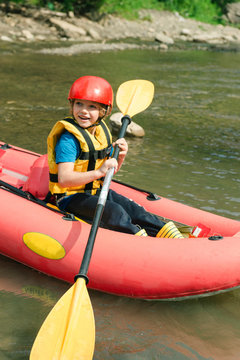 Happy boy ready to row on raft on the river