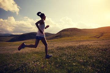 young fitness woman runner running on grassland trail