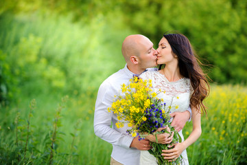 two lovers having a rest outdoors, a girl with a bouquet of wildflowers.