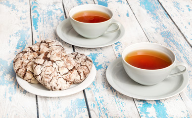 Two cups of tea with cookies on the table.