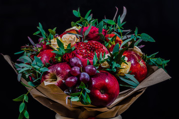 fresh autumn vegetarian fruity bouquet of apples, grapes, pomegranates and roses, with green leaves on a dark background - 175852440