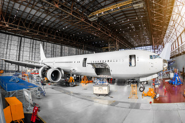 Large passenger aircraft in a hangar on service maintenance. - obrazy, fototapety, plakaty
