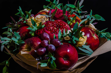 fresh autumn vegetarian fruity bouquet of apples, grapes, pomegranates and roses, with green leaves on a dark background - 175852457
