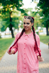 young woman with braids in a summer park in pink clothes in summer outdoors