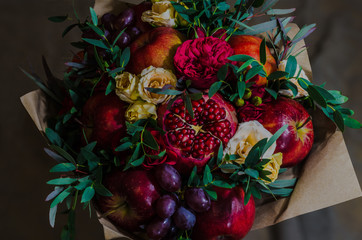 fresh autumn vegetarian fruity bouquet of apples, grapes, pomegranates and roses, with green leaves on a dark background - 175852471