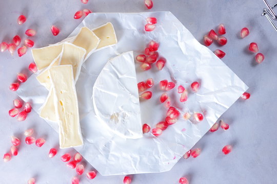 Camembert cheese, sliced cheese, lots of cheese with pomegranate seeds on white background