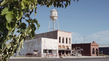 Abandoned Ghost Town with Water Tower. shot moves from a tree and reveals an abandoned ghost town main road with a water tower
