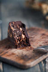 Raw chocolate brownies cake with hazelnuts on rustic wooden table. Dark food photography