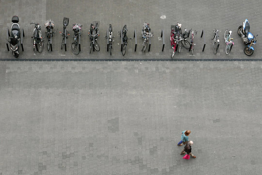 Vogelperspektive auf eine Reihe von geparkten Fahrrädern und Motorrädern und zwei Fußgänger