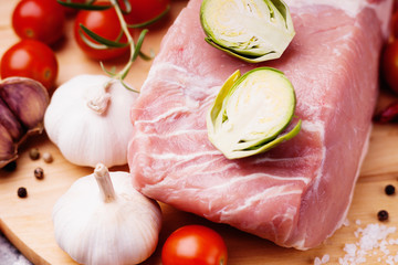 Raw pork on cutting board and vegetables 