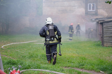 Naklejka premium The team of firefighters eliminates the fire in an old building