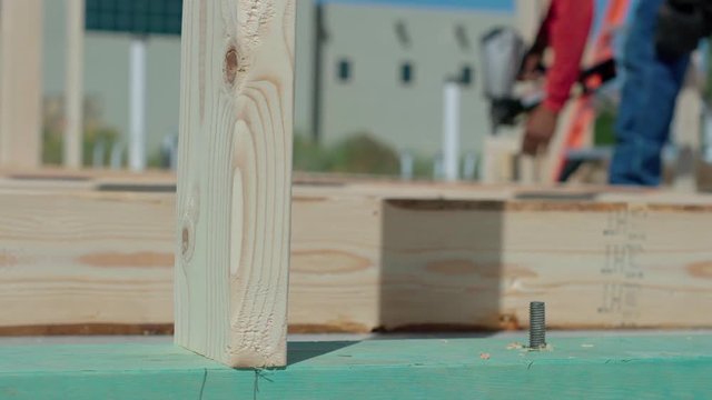 Wood Framing Close Up Move Right with Worker. view moves right on a close up on the end of a framed wall on the construction site with a construction worker in the background
