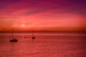 Fototapeta premium Beautiful colorful sunset at the sea with two sailing boats . Beauty world natural outdoors travel background