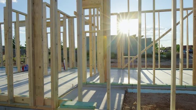 Move Right Around Corner of Framed Residential Home. view moves right as sun flare wraps around the beams of the new residential home framing wood walls
