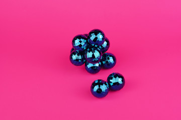 Imagen minimalista de bolas de espejo azul amontonadas sobre un fondo rosa fucsia