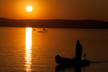 Naklejka na ściany i meble Beautiful sunset over Lake Balaton with anglers' silhouettes in Hungary