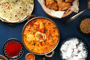 Indian cuisine on diwali holiday: tikka masala, samosa, patties and sweets with mint chutney and spices. Dark blue background