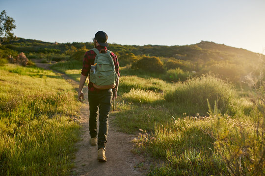 male millennial hiker walking trail in california during sunset