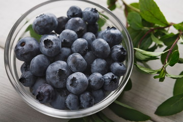 Bowl of blueberries and mint sticks on rustic wood