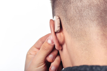 Young man hearing impaired dressing the hearing aid. At isolated white background.