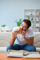 Man eating pizza having a takeaway at home relaxing resting