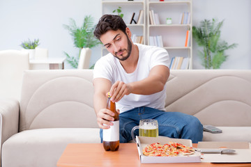 Man eating pizza having a takeaway at home relaxing resting