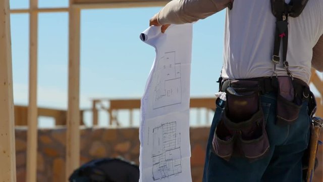 Construction Worker Flipping Through Blueprints. a close up shot of a contractor flipping through the blueprints on site at a residential build

